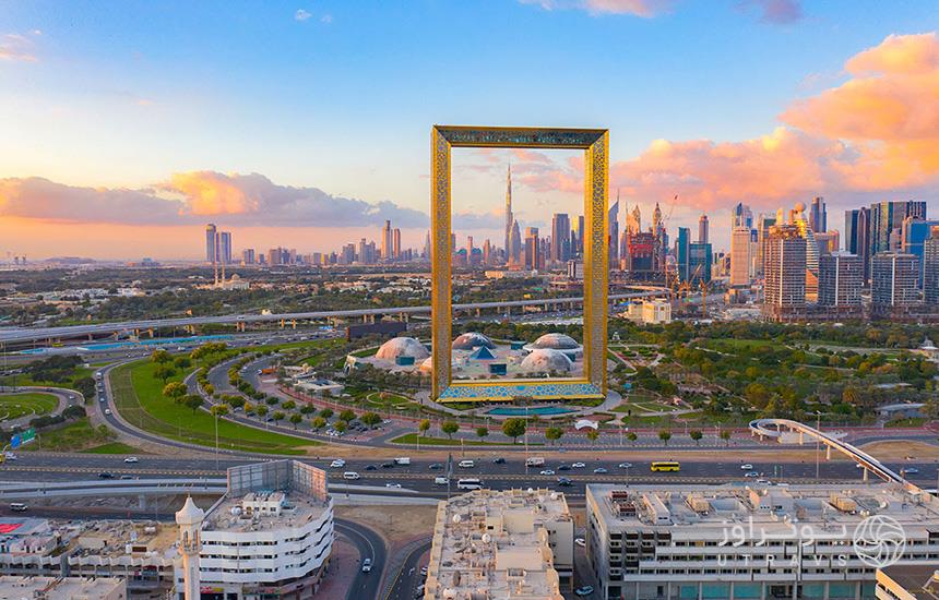 عکسی از روبه‌رو از قاب دبی که مستطیلی طلایی‌رنگ است و در پس‌زمینه‌اش آسمان‌خراش‌ها و برج‌های دبی دیده می‌شود.